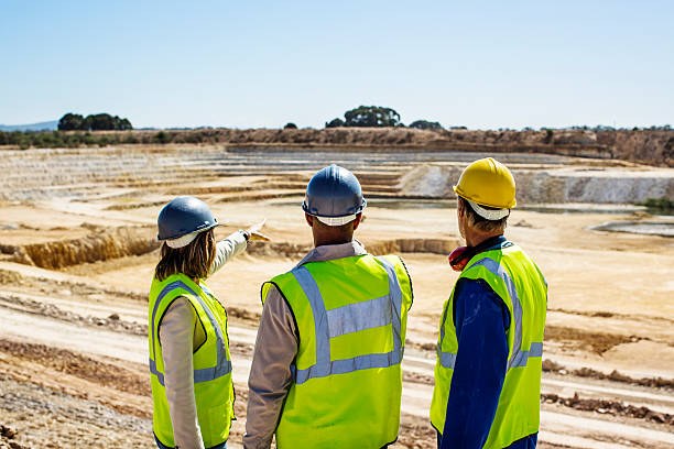 Architects and construction worker examining quarry against clear sky
